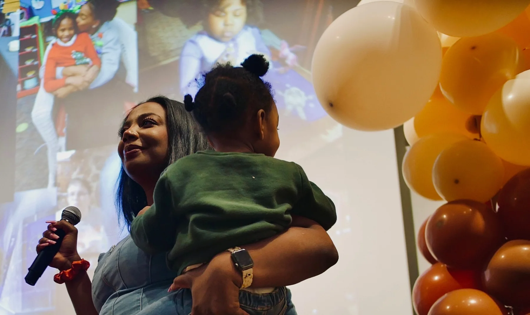 Kyra Betts speaking while holding a young child